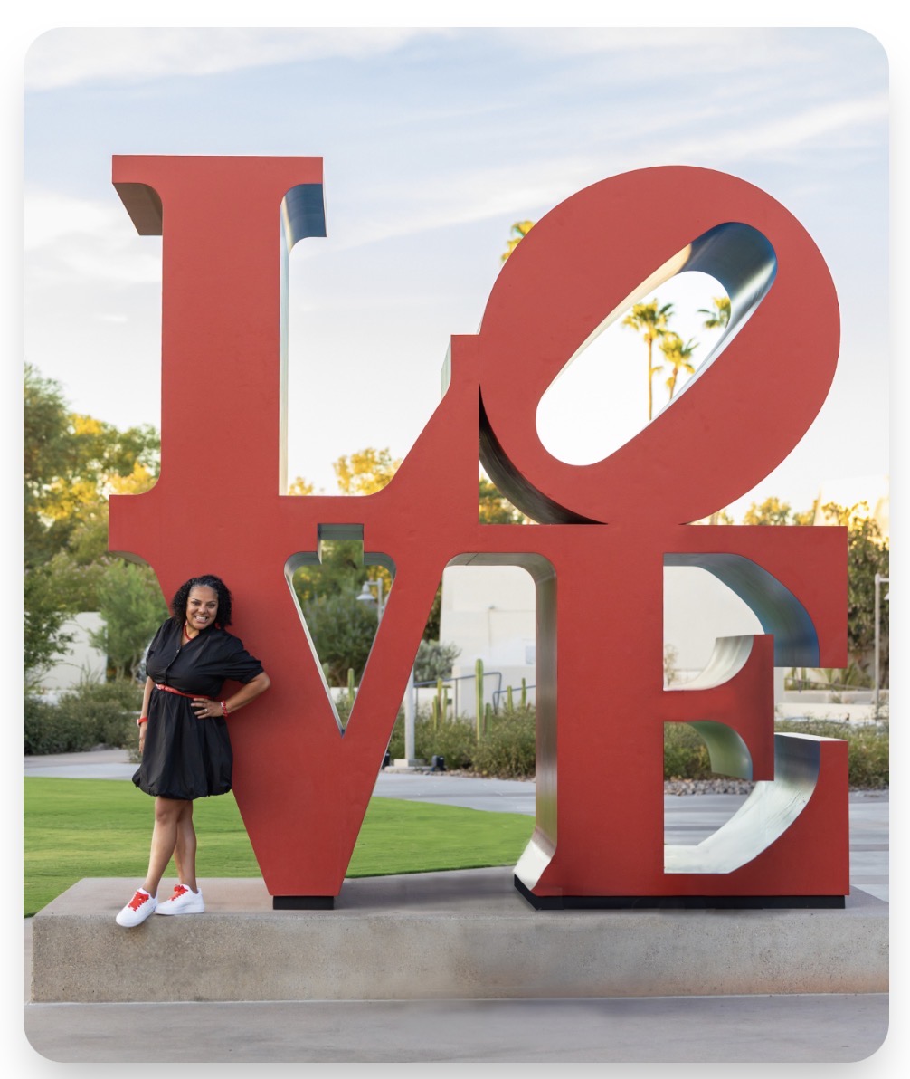 Jazmine Hall standing beside a large red LOVE sculpture